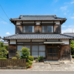 徳島県によく見られる築50年の瓦屋根木造二階建て住宅の外観。青空の下に立つ30坪程度の標準的な一軒家。