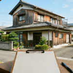 徳島市・阿南市エリアの木造二階建て住宅と、解体工事の見積もりをイメージした白紙のバインダー