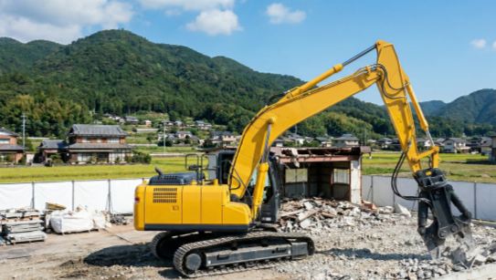 徳島の解体現場で稼働する、低騒音・低振動のコンクリート圧砕機付き黄色油圧ショベル（ご近所トラブル対策）