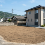 徳島市での住宅建て替えに伴う解体工事完了後の写真。手前に綺麗に整地された更地が広がり、右隣には既存の2階建て住宅が立つ。
