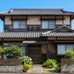 徳島の住宅街にある、青空を背にした伝統的な木造二階建ての一軒家。解体前に重要な準備を進めている。手前には電柱とアジサイの咲く外構。