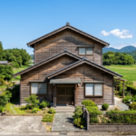 青空の下、田んぼに囲まれた場所にある、徳島の市街化調整区域によく見られる解体前の木造2階建ての一軒家。