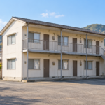 建物全体と外階段、駐輪場、重機の進入経路が分かる実際の現場写真